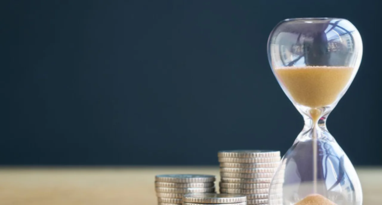 An hourglass next to a stack of coins