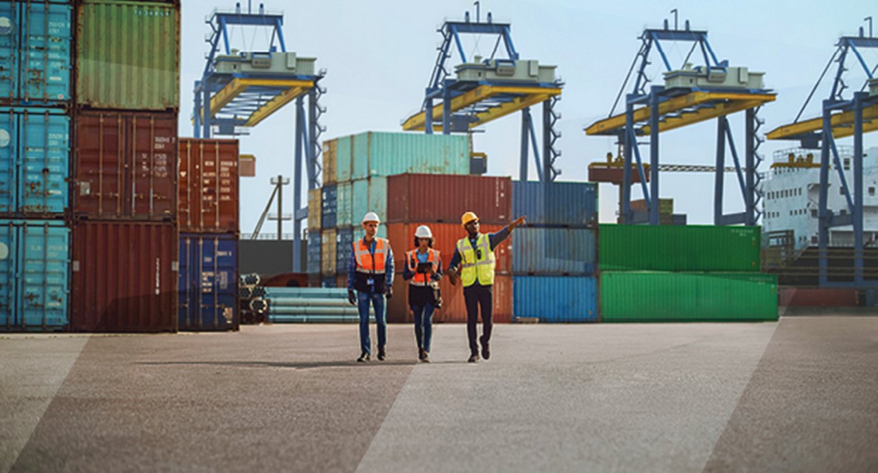 three workers inspect a container port
