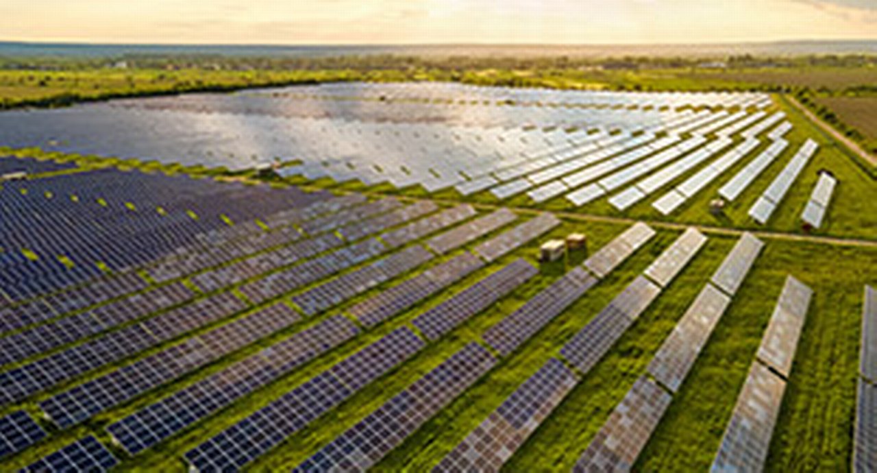 Aerial view of large sustainable electrical power plant with many rows of solar photovoltaic panels for clean ecological electric energy at sunrise