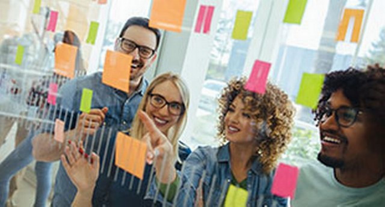 Business team brainstorming in front of glass wall with adhesive notes