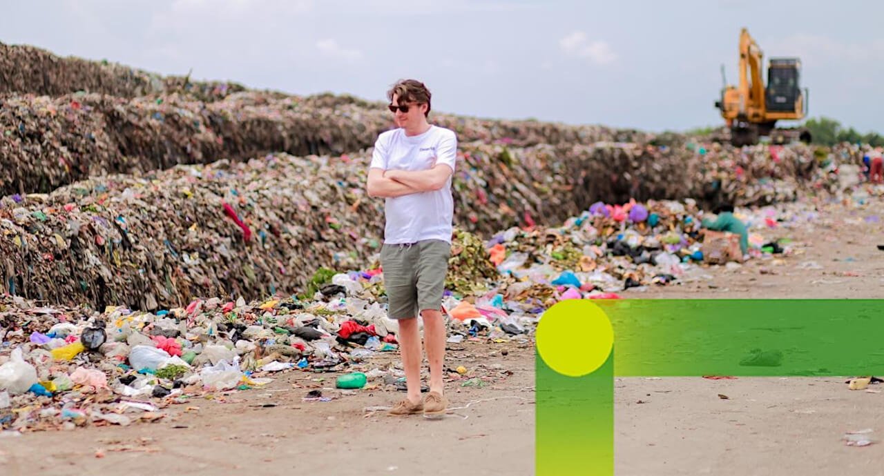 Man on the beach in front of a pile of garbage