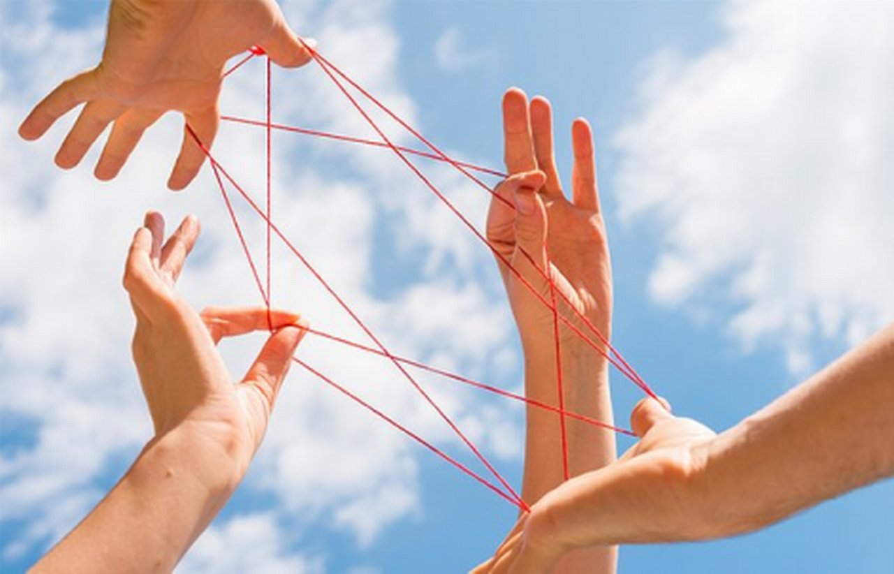 hands forming a pattern with a red string