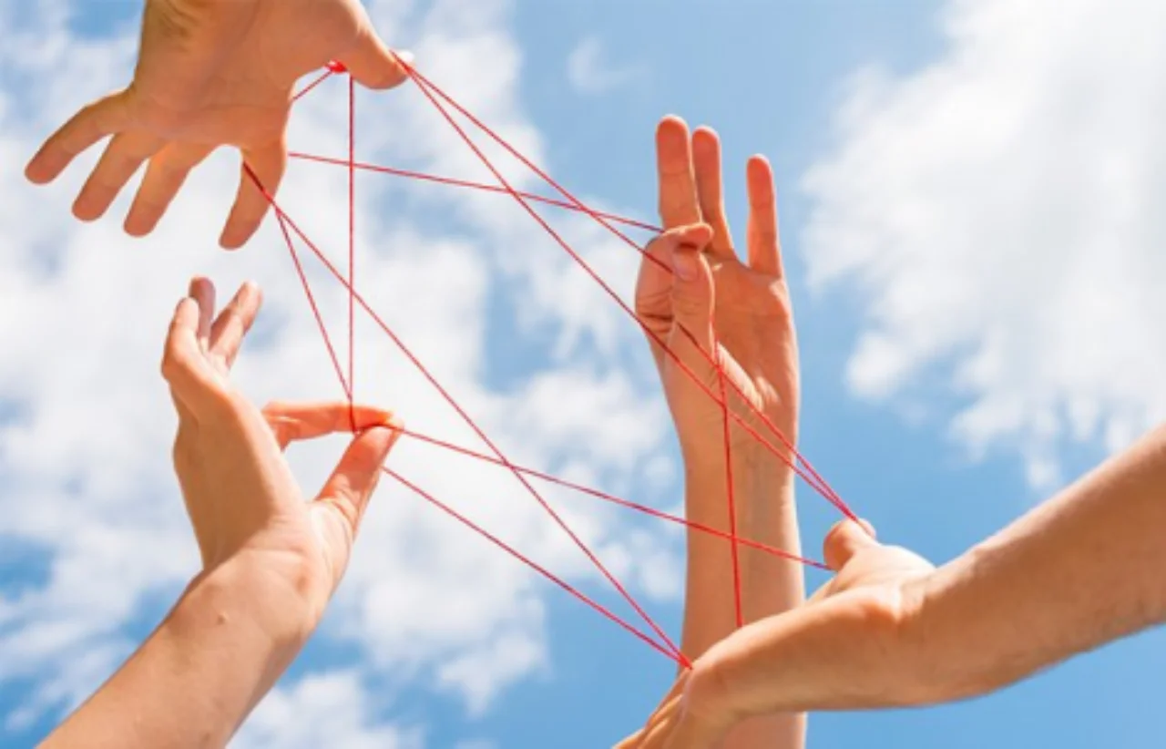 hands forming a pattern with a red string