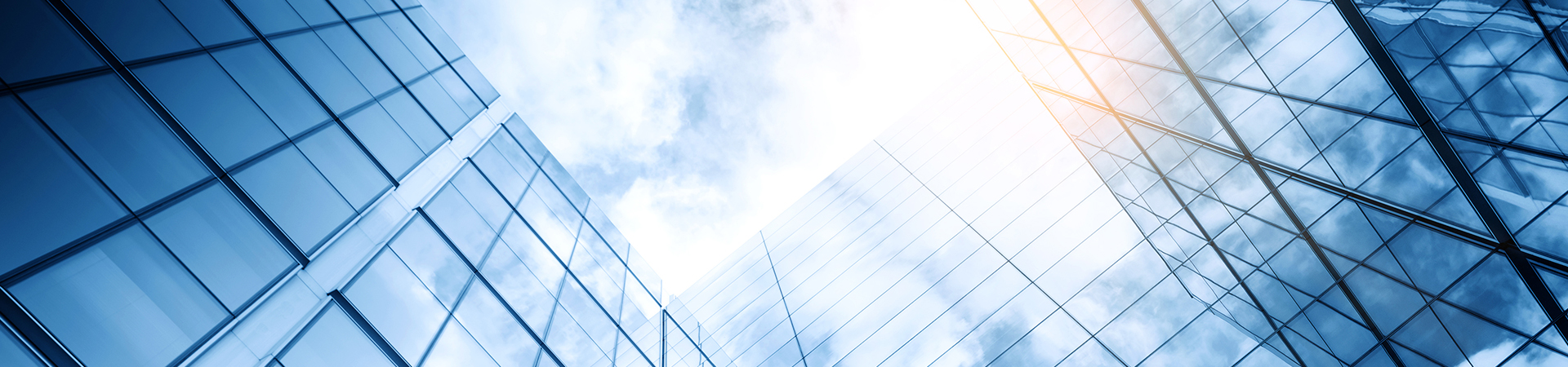 Two glass office building reflecting the sky overhead