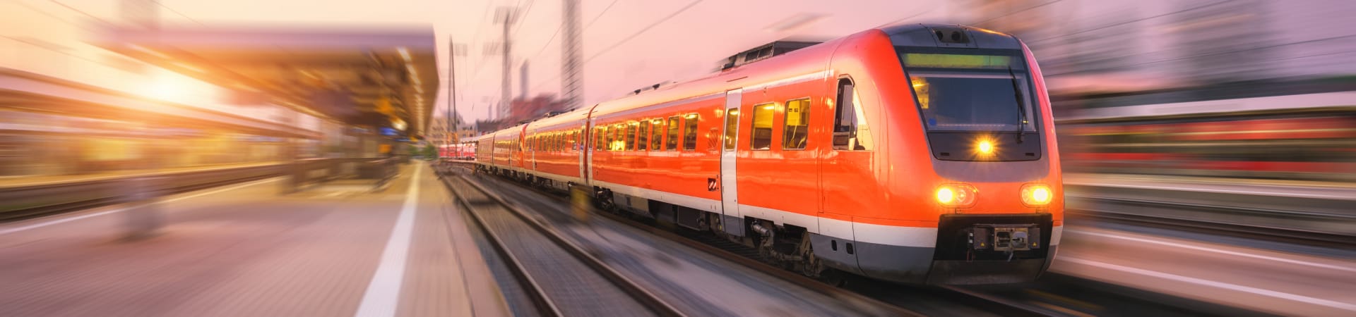 High speed red train with motion blur effect on the railway station at sunset